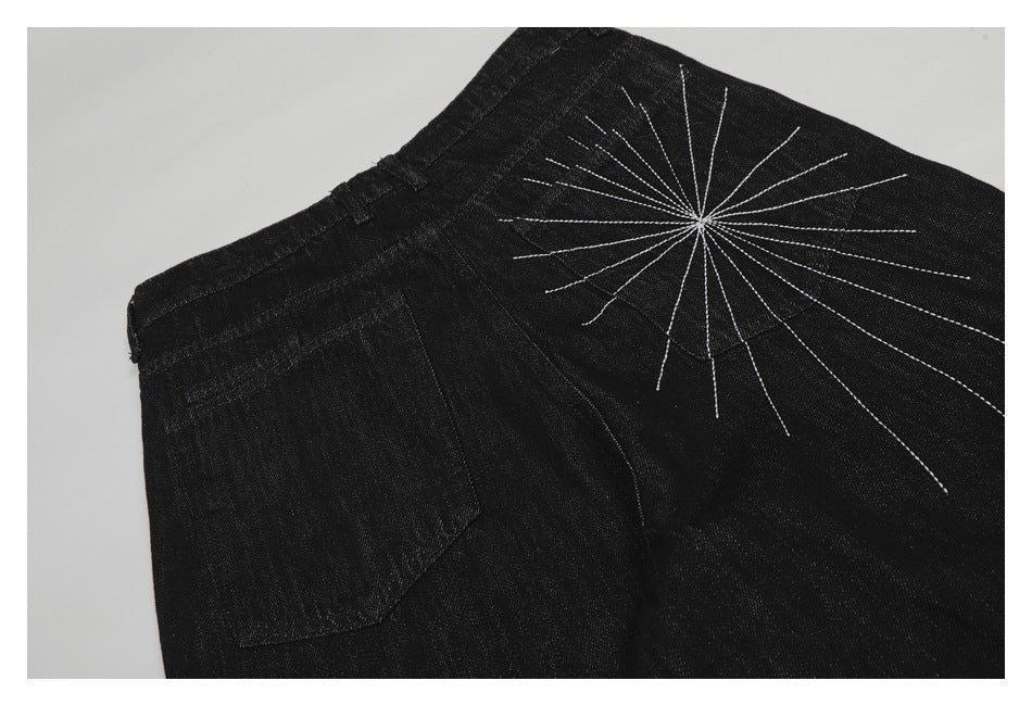 Back pocket detail of black jeans with a large white radiating stitched design.