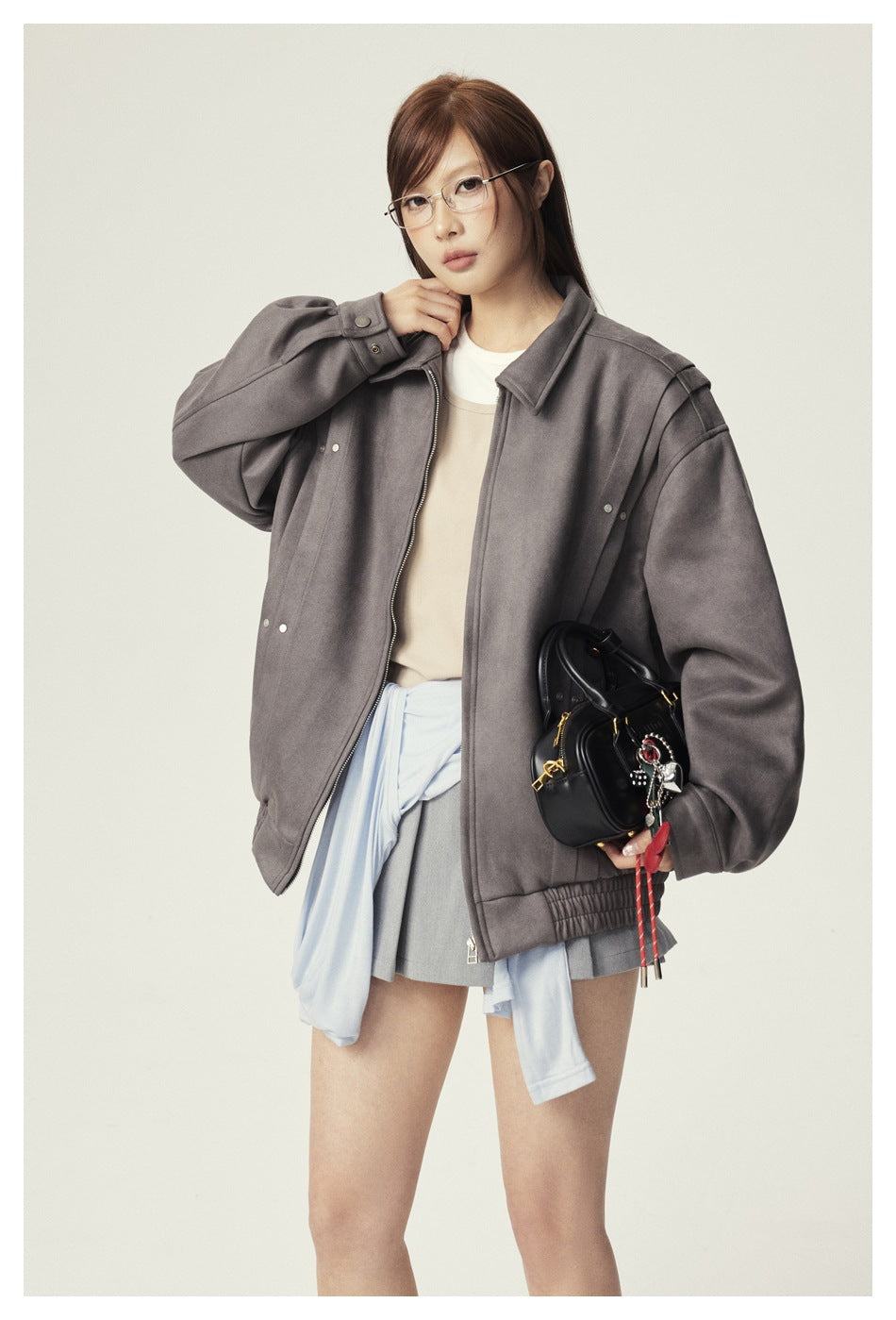 Model wearing an oversized gray zip jacket with a beige top and gray skirt.