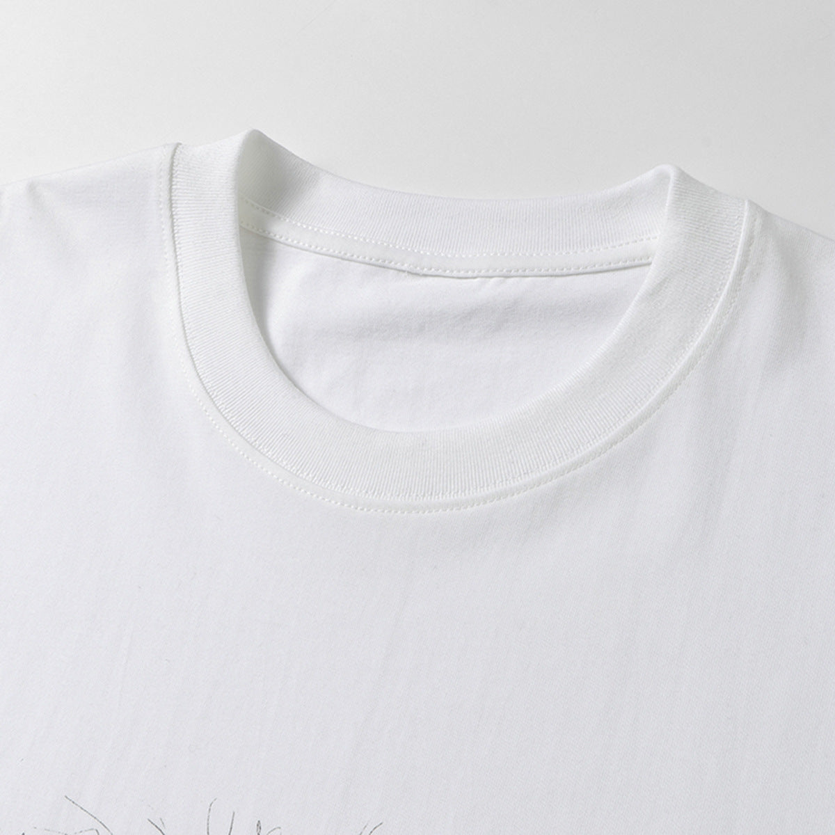 Close-up of a white T-shirt's ribbed crew neckline and shoulder seams.