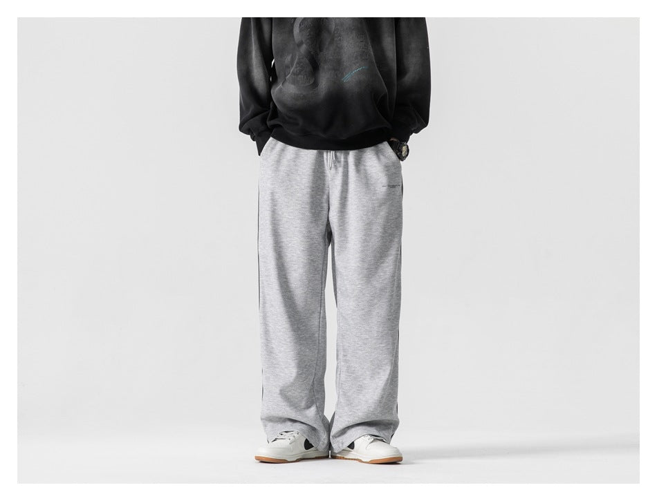 Person wearing light gray wide-leg pants with a black faded sweatshirt and white sneakers, front view