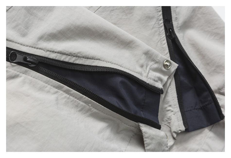 Close-up of an open zip pocket on light gray-beige pants, revealing dark lining and black zipper tape.