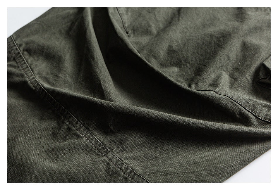 Close-up of olive trouser fabric draped to show a stitched seam and folds.