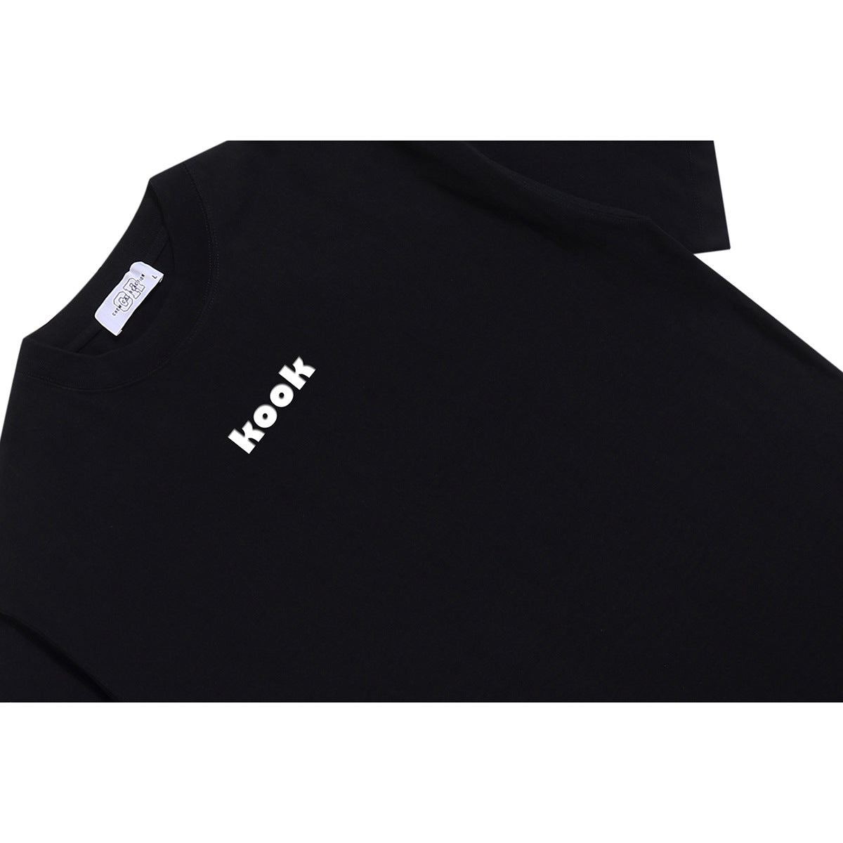Close-up of a black T-shirt with a small white “kook” chest print and a white neck label.