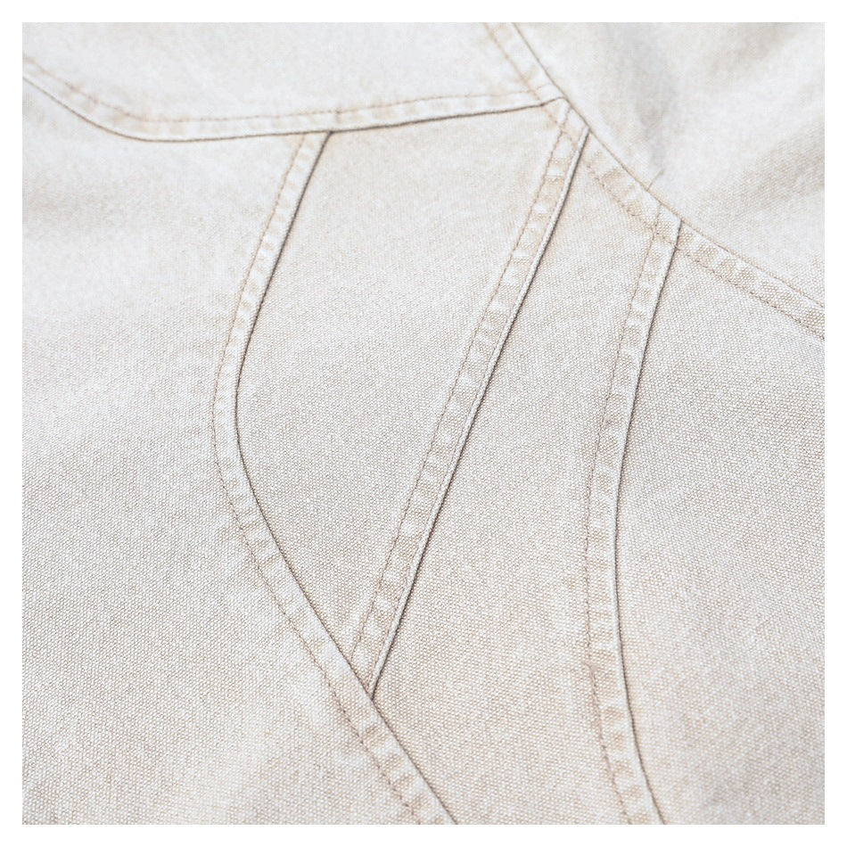 Close-up of a light beige jacket’s overlapping front panels and curved topstitching.