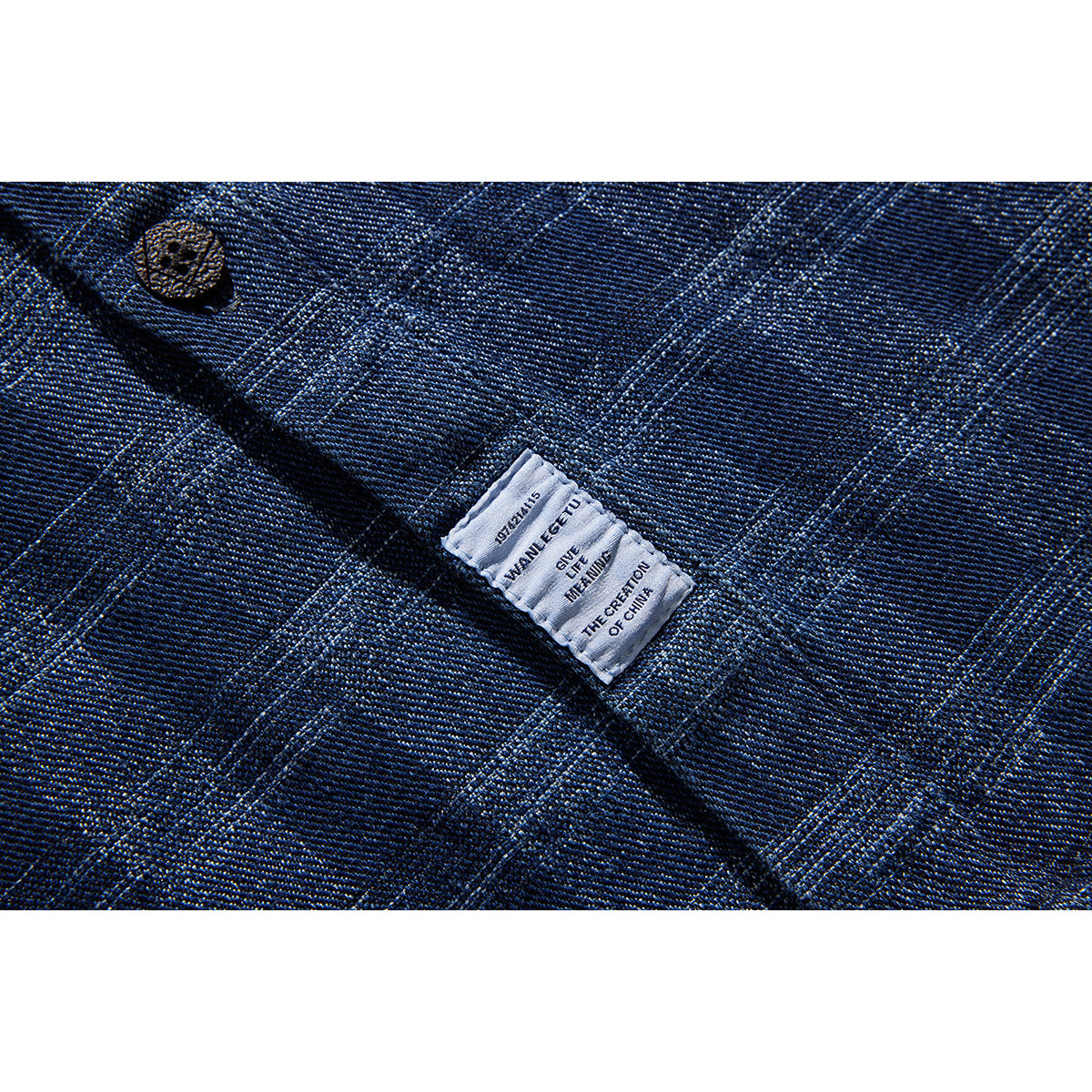 Close-up of a blue plaid shirt's woven fabric, button, and sewn care label with English text.