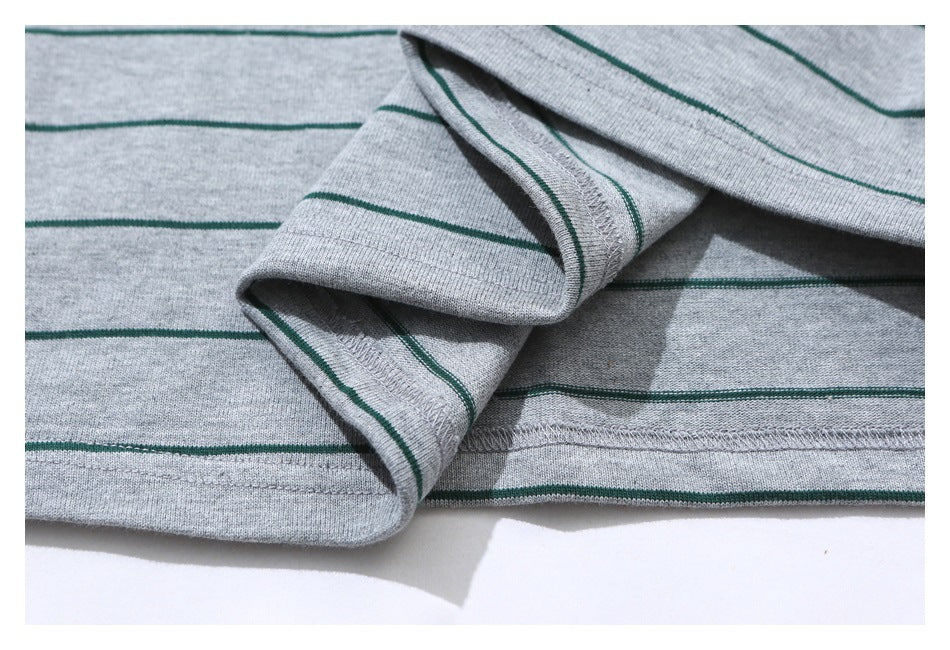 Close-up of a gray T-shirt's striped fabric, sleeve seam, and stitched bottom hem.