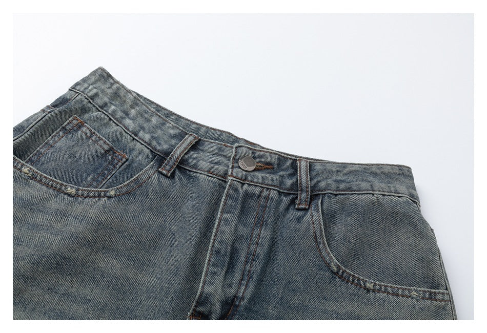 Close-up of the front waistband, belt loops, button, fly, and pockets on faded blue jeans.