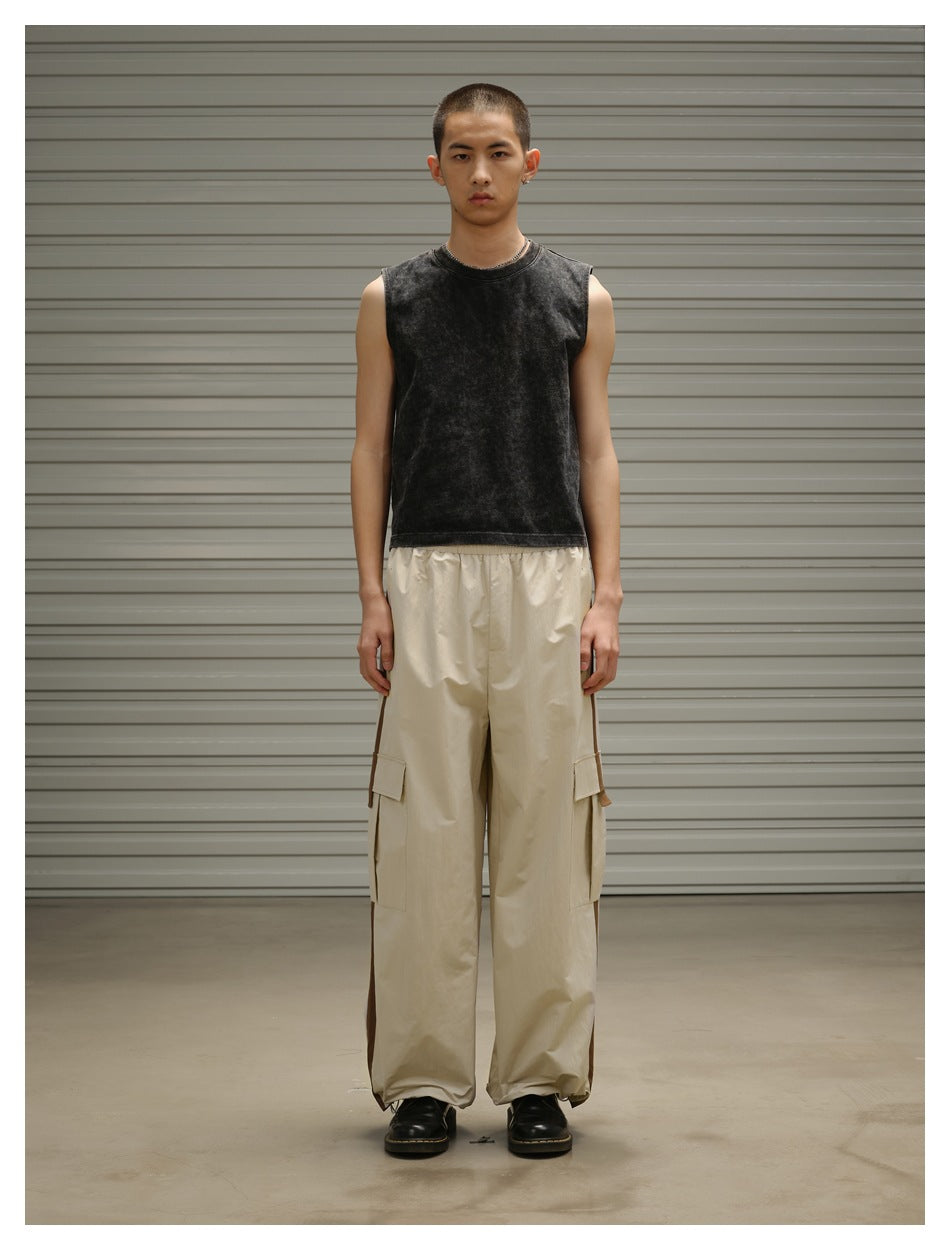 Model standing in light khaki wide-leg cargo pants with brown side stripes, a dark tank top and black shoes