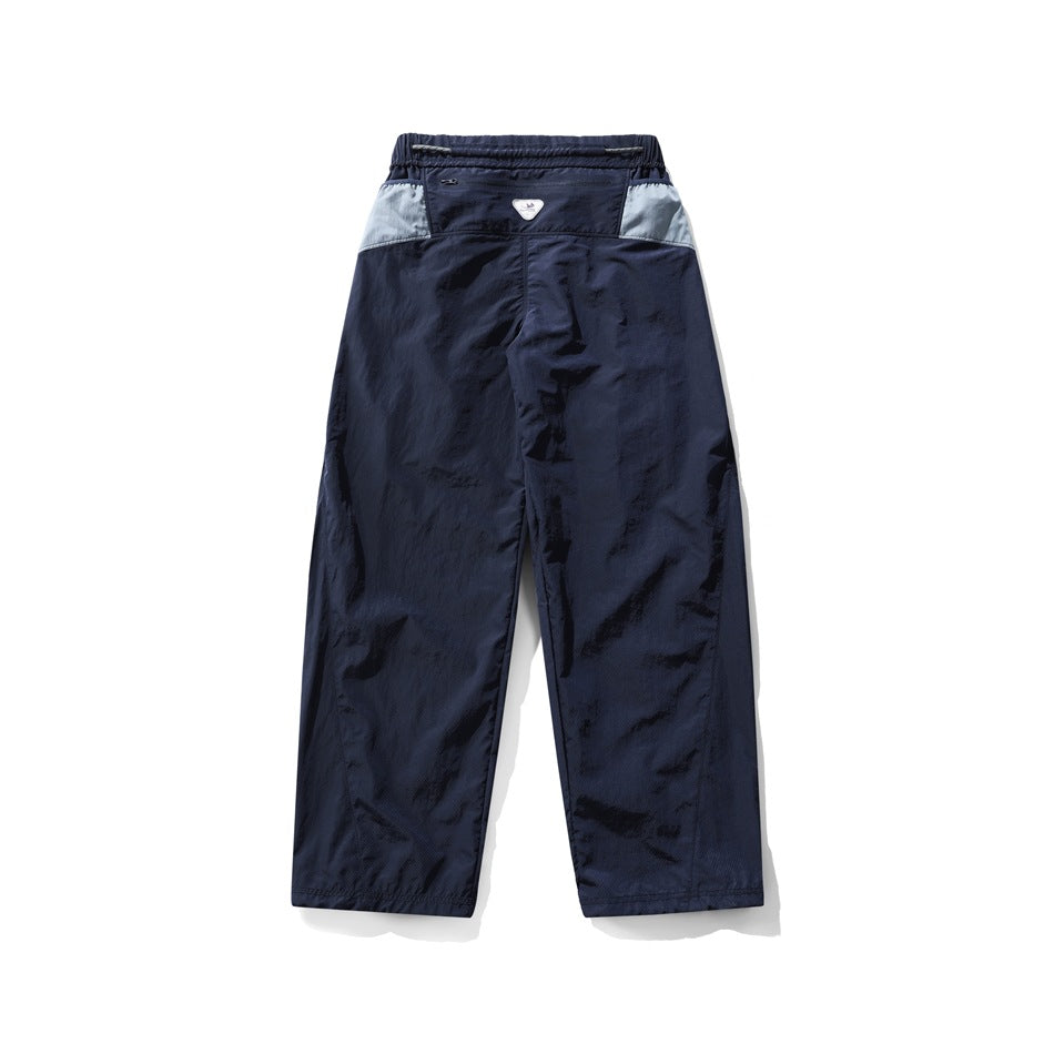 Back view of loose navy pants with pale blue panels at the waistband sides and an elastic waist.