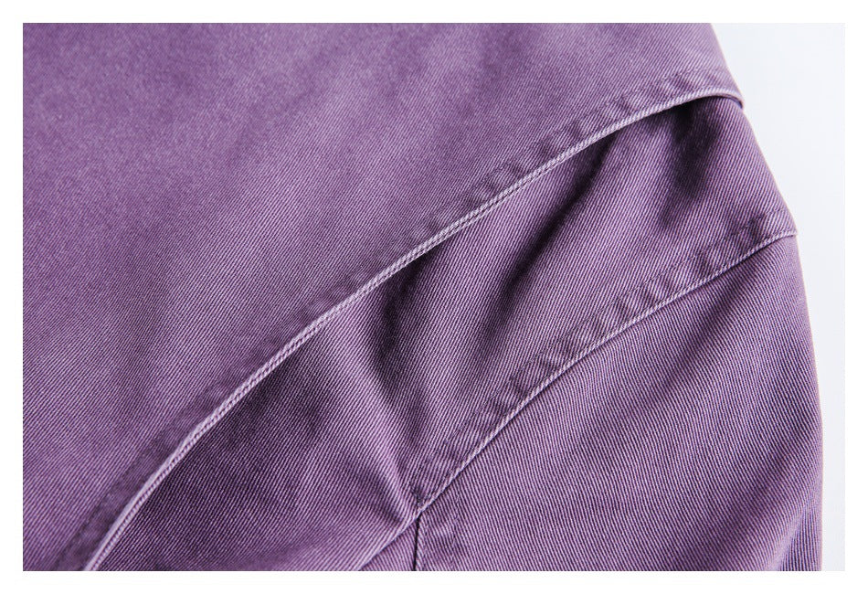 Close-up of curved stitched panels on purple garment fabric.