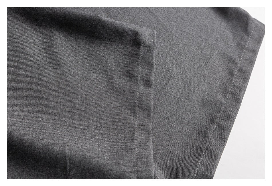 Close-up of charcoal gray trouser fabric with a vertical seam and stitching.