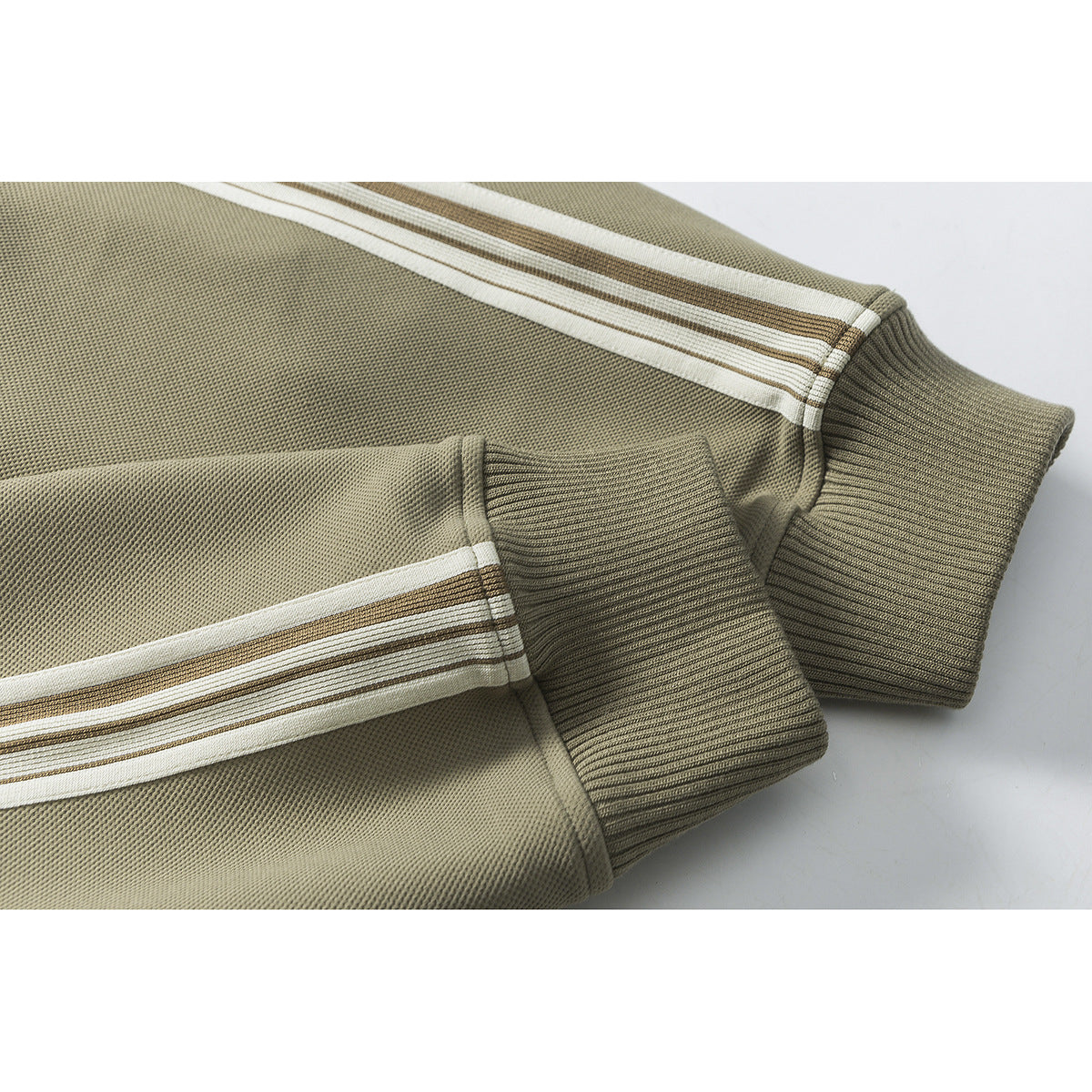 Close-up of an olive jacket sleeve with cream and brown stripes and a ribbed cuff.