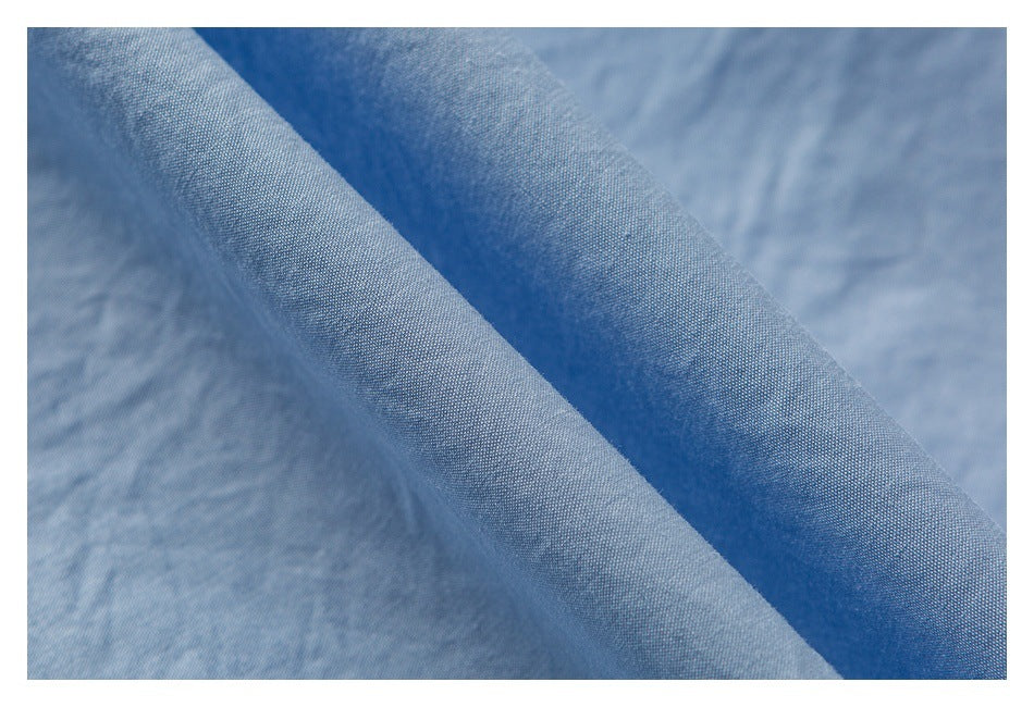 Close-up of light blue fabric draped in folds, showing its fine woven texture.