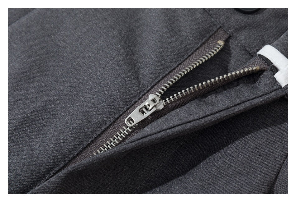 Close-up of the partially open metal zipper and fly on charcoal gray trousers.