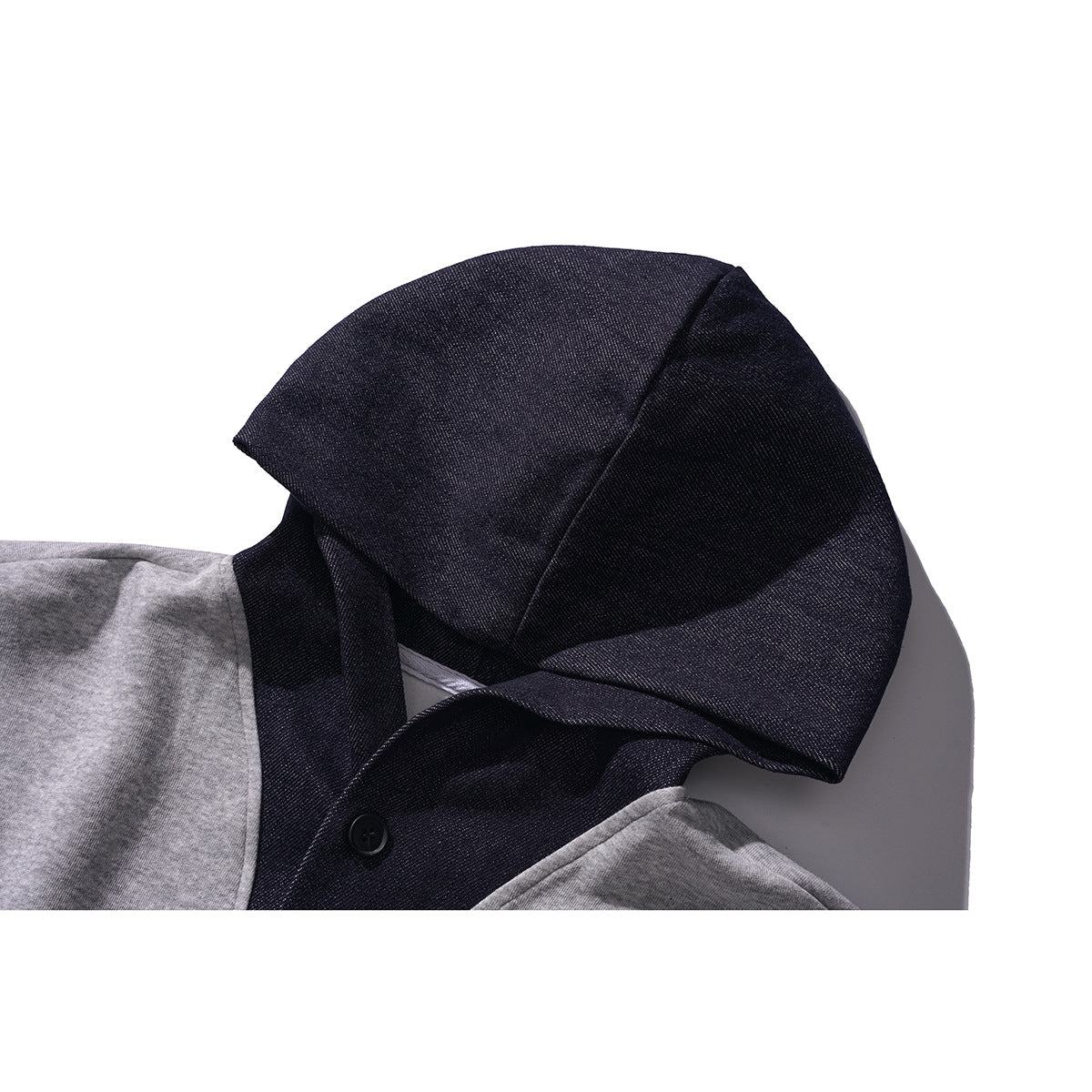 Close-up of a dark hood and buttoned neckline on a gray hooded pullover.