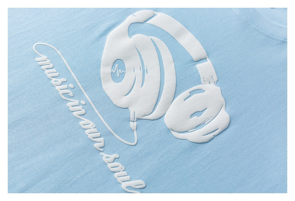 Close-up of a raised white headphone graphic and “Music in our soul” lettering on light blue fabric.