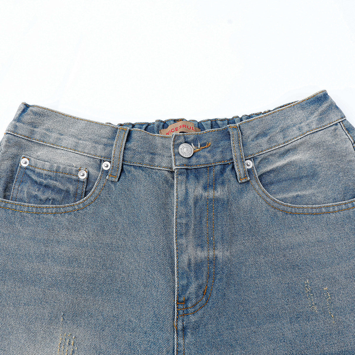 Close-up of light blue jeans showing the waistband, button, front pockets, fly, and faded distressed marks.