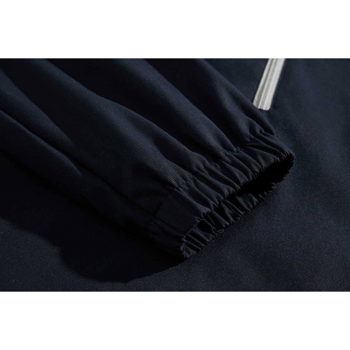 Close-up of the navy jacket's gathered elastic cuff beside a light gray zipper.