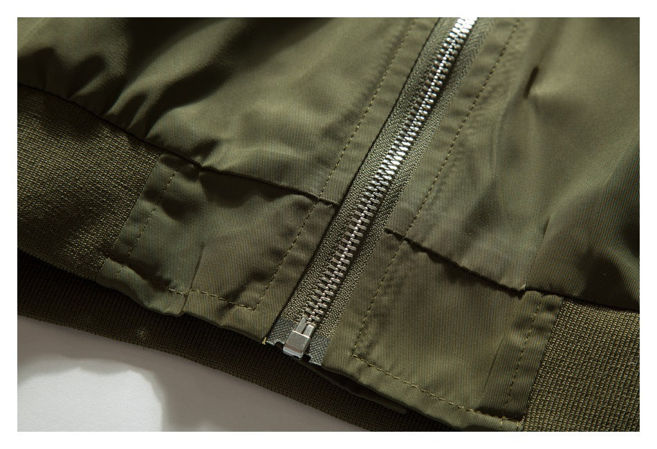 Close-up of an olive jacket hem showing the metal front zipper and a wide ribbed waistband.