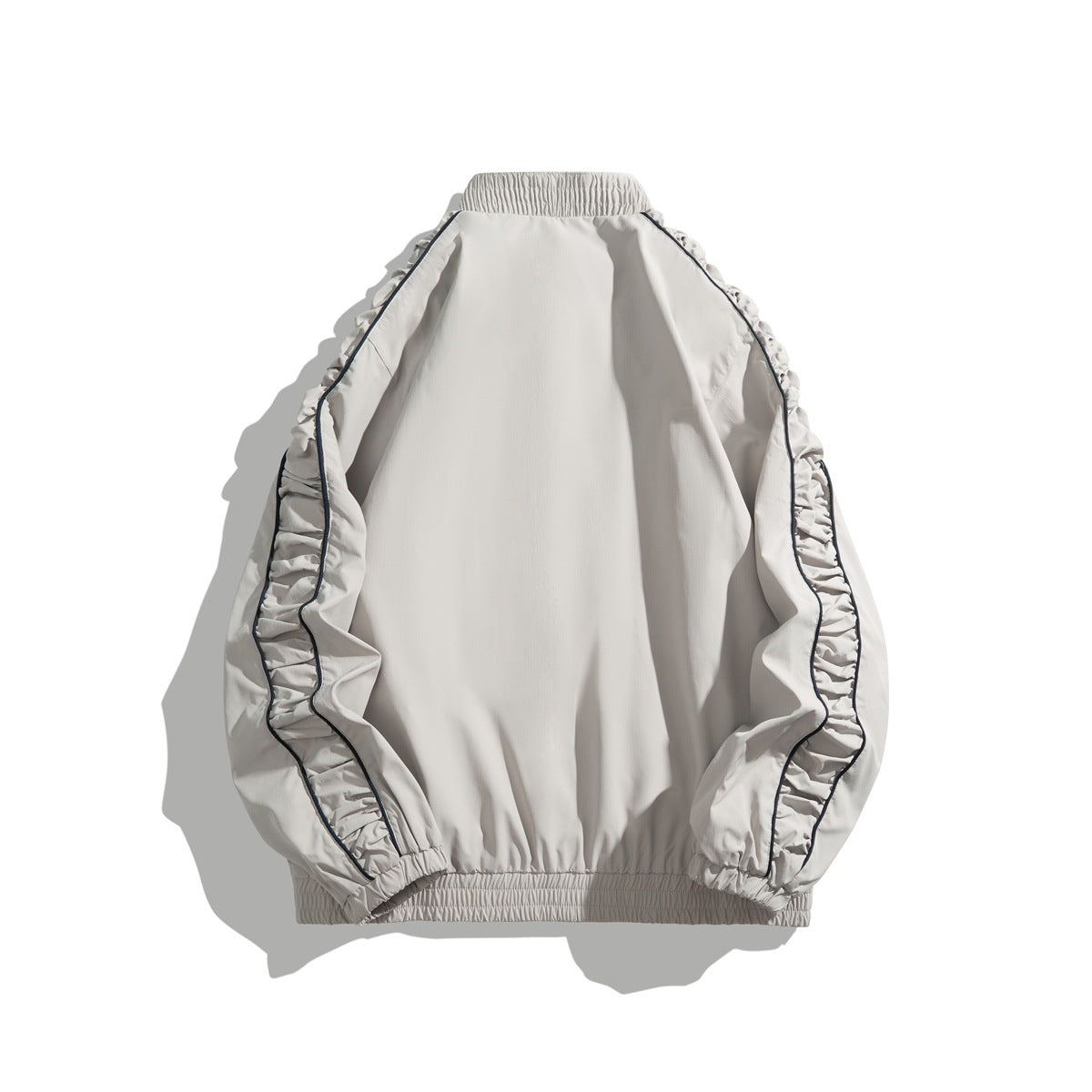 Back view of light gray-beige jacket with ruched raglan sleeves, navy piping, elastic cuffs and hem, and stand collar