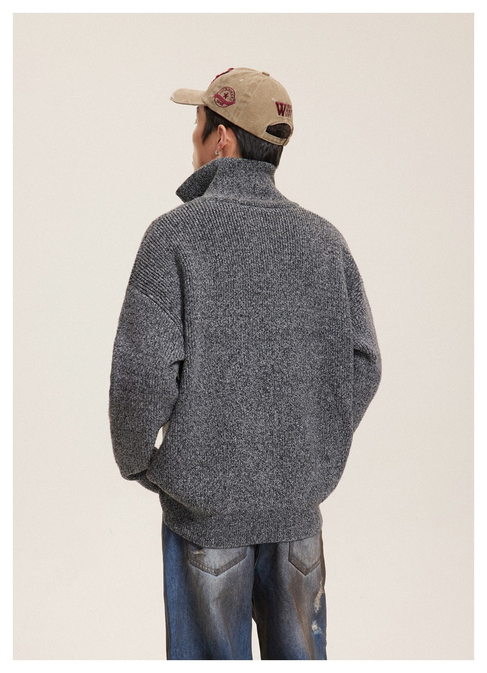Back view of a model wearing a charcoal textured cardigan with a raised collar and loose blue jeans.