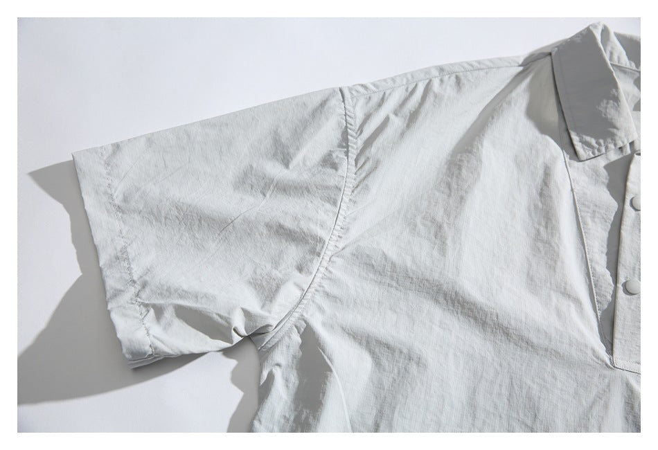 Close-up of the light gray pullover's short sleeve, shoulder seam, and button placket edge.