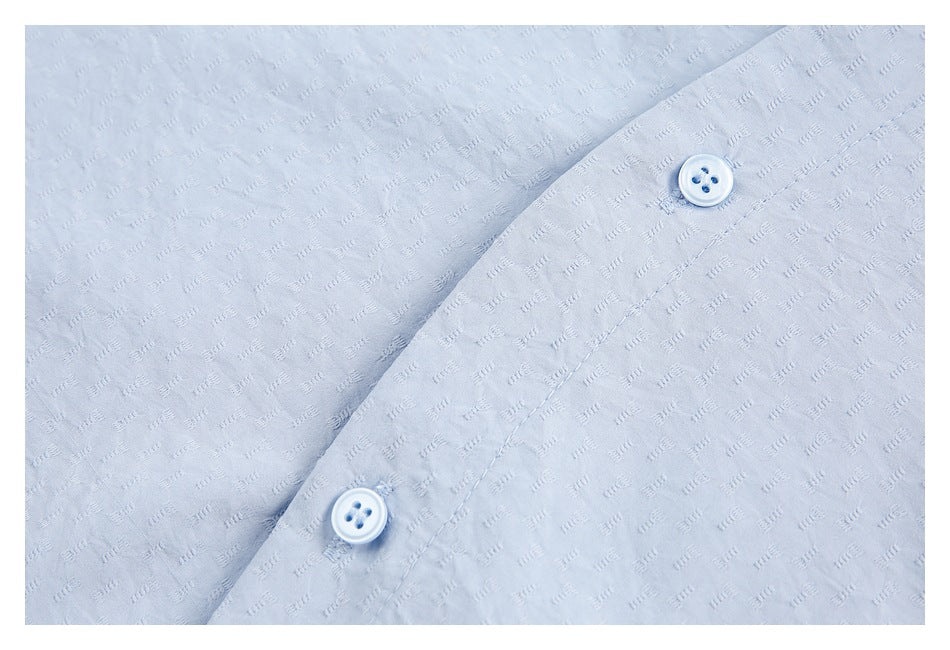 Close-up of light blue textured shirt fabric and two buttons on the placket.