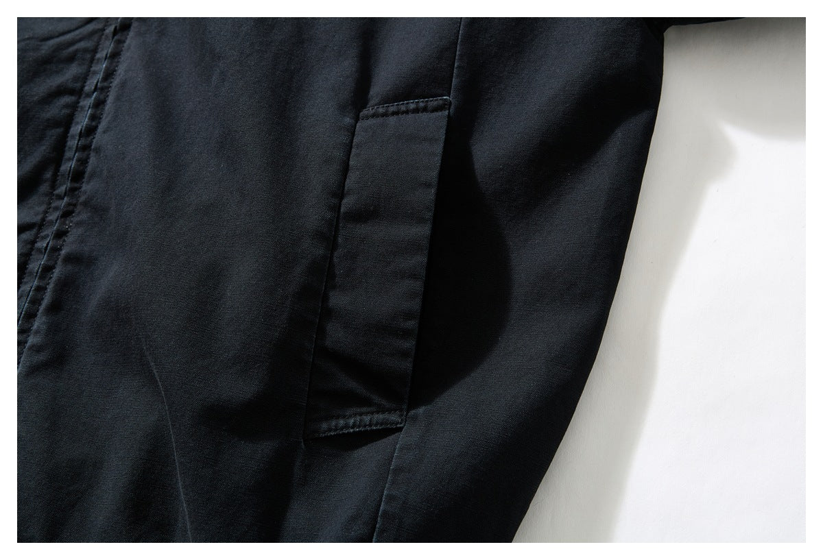 Close-up of a black garment's rectangular side pocket and stitching.
