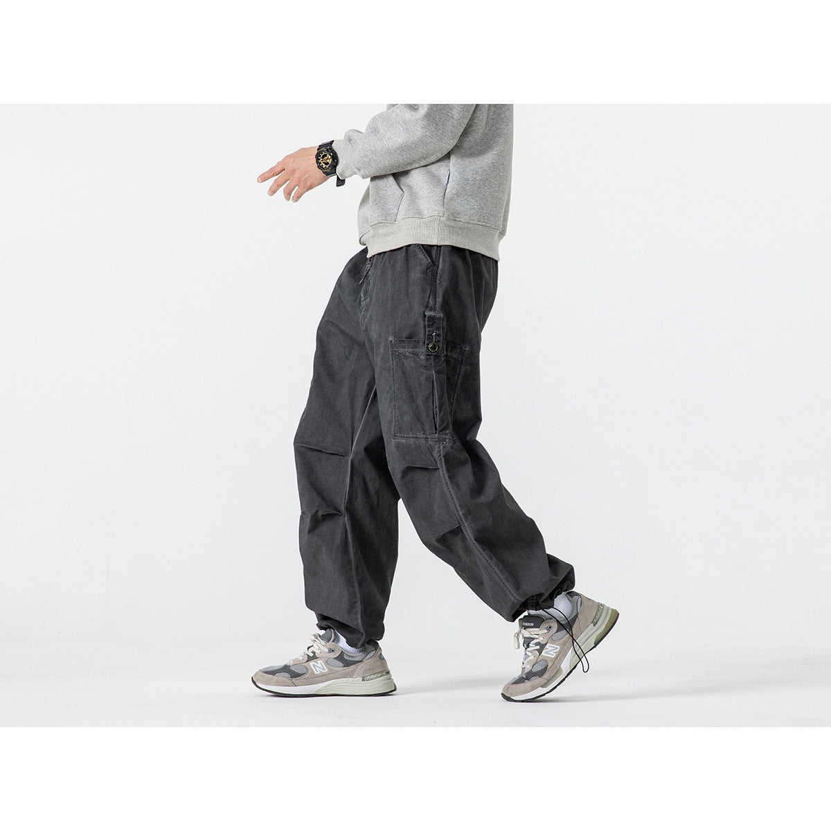 Side view of a model wearing charcoal wide-leg cargo pants with a large side pocket and gray sweatshirt.