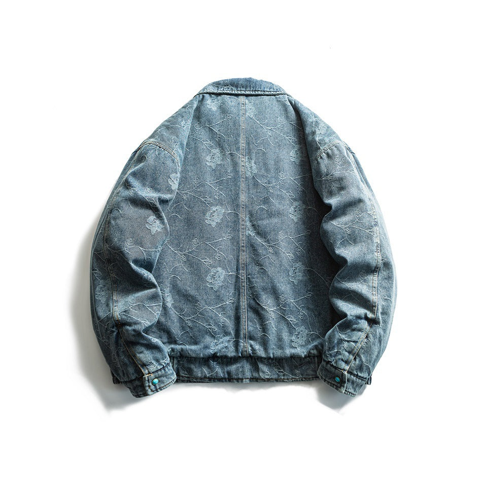 Back view of a blue denim jacket with a subtle floral vine pattern, long sleeves, and gathered cuffs and hem.