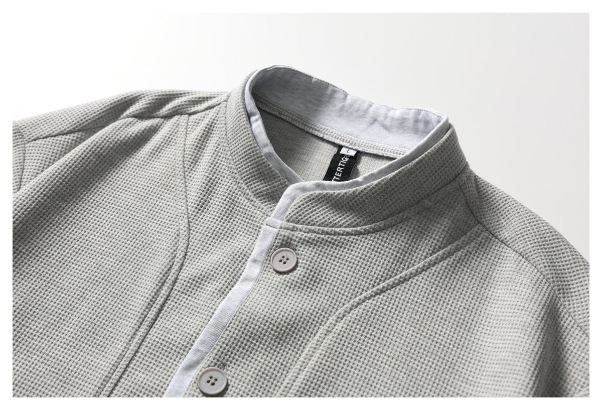 Close-up of a light gray textured button-front top with a stand collar and pale placket trim.