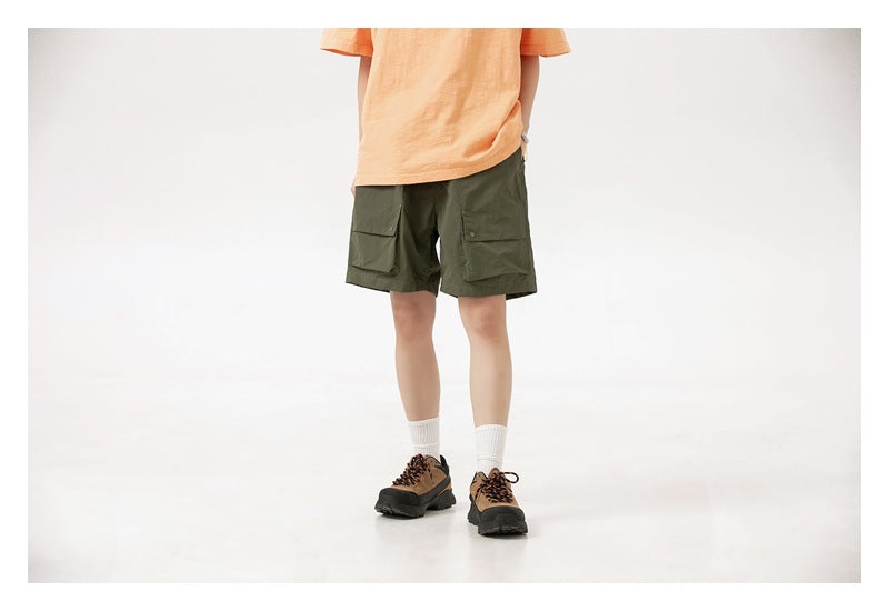 Front view of a model wearing olive green cargo shorts with two flap pockets and an orange T-shirt.