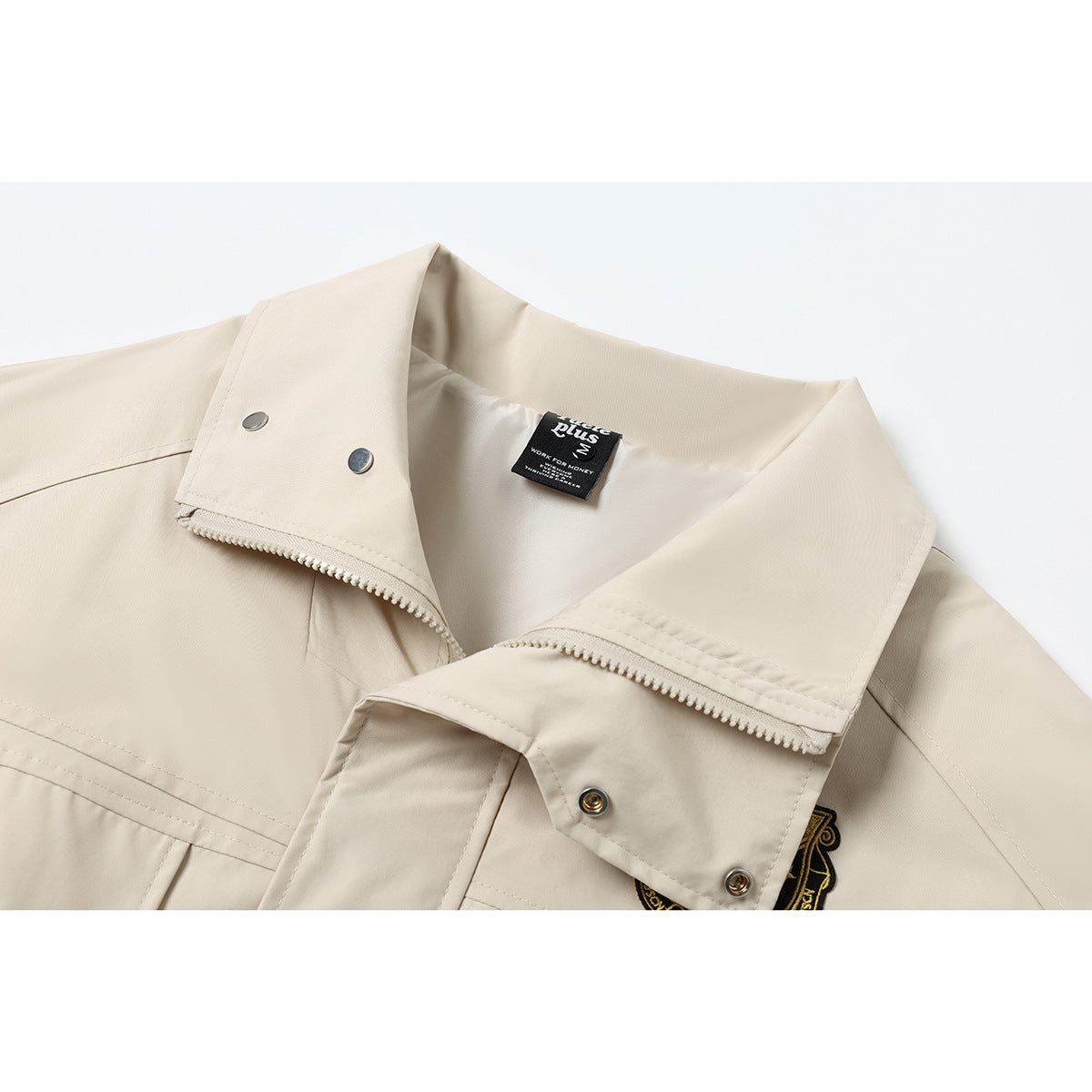 Close-up of a light beige jacket collar, zipper, snap fasteners, and sewn-in neck label.