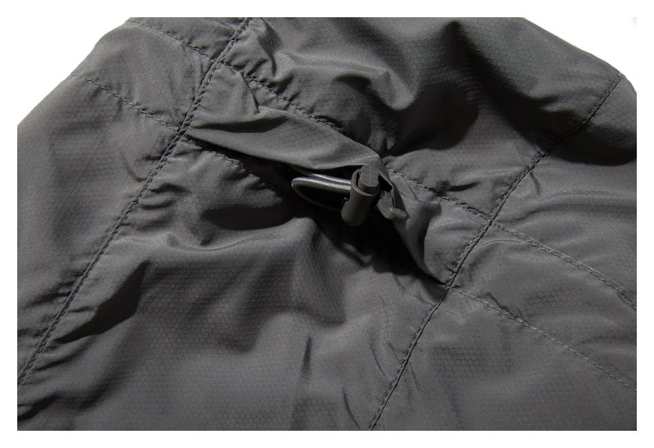 Close-up of a dark gray garment's adjustable drawcord toggle and stitched panels.