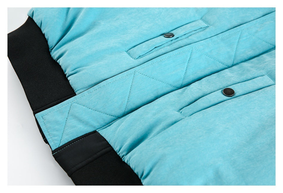 Close-up of a turquoise jacket showing snap-button pocket flaps, stitched panels, and black ribbed trim.