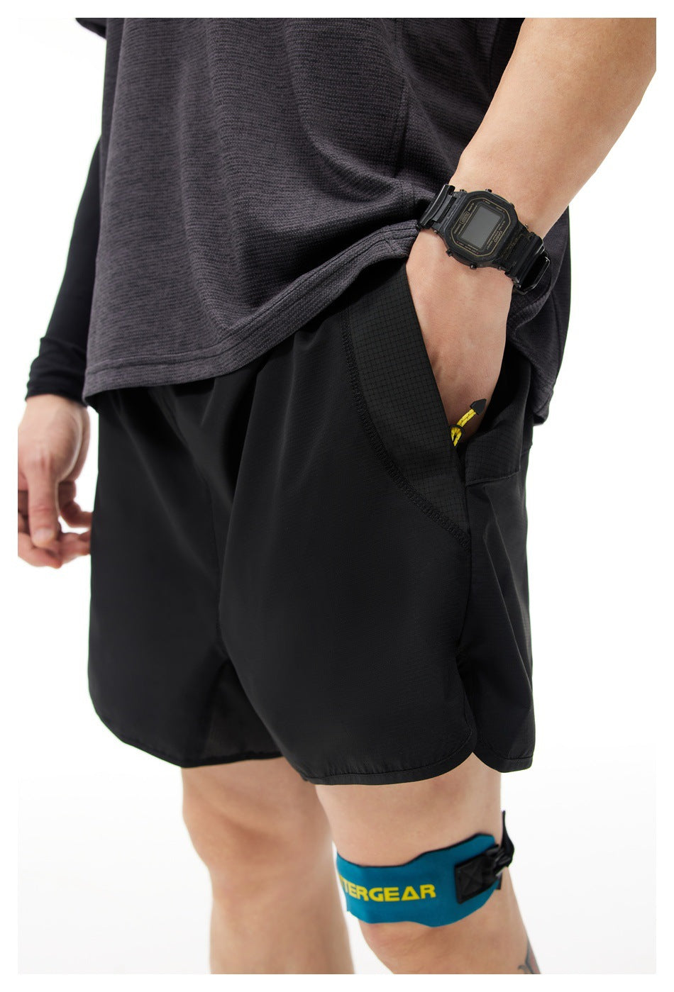 Close-up of black athletic shorts with a textured side pocket and zipper, worn with a dark shirt.