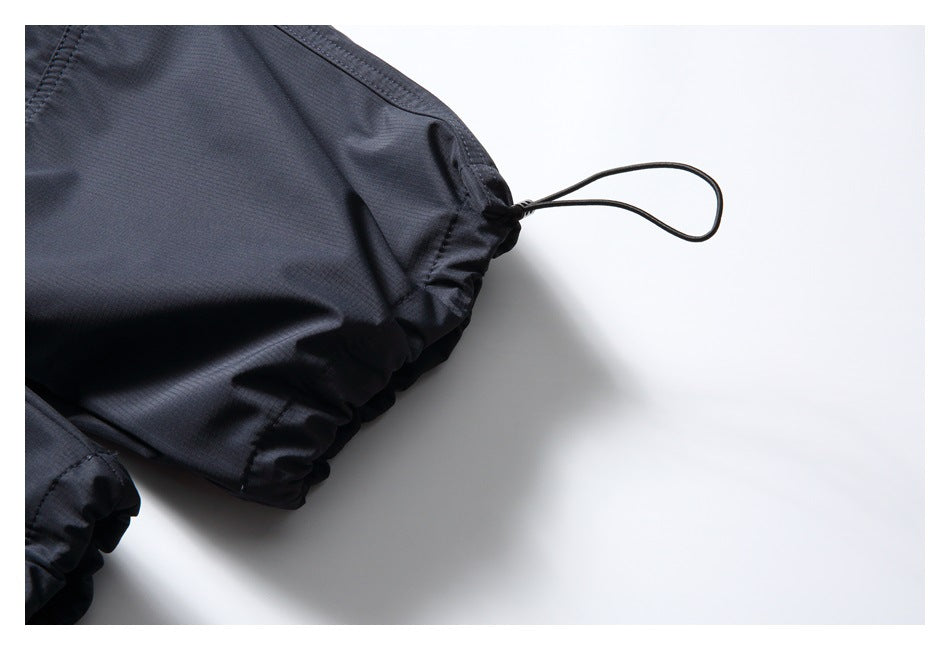Close-up of a dark trouser cuff with an elasticated edge and looped drawcord.