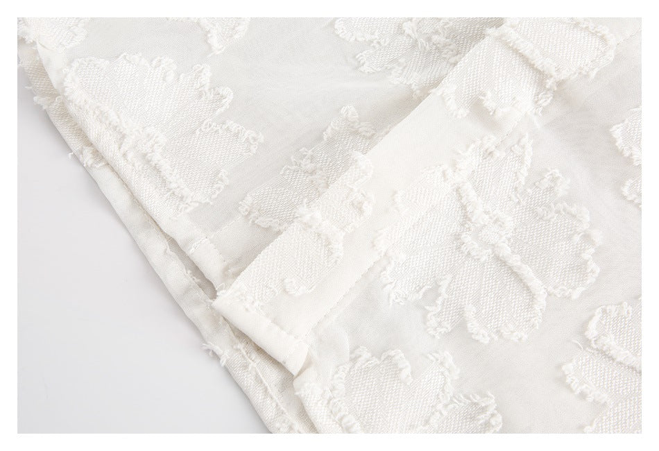 Close-up of ivory floral-textured fabric showing a folded edge and stitched seam.