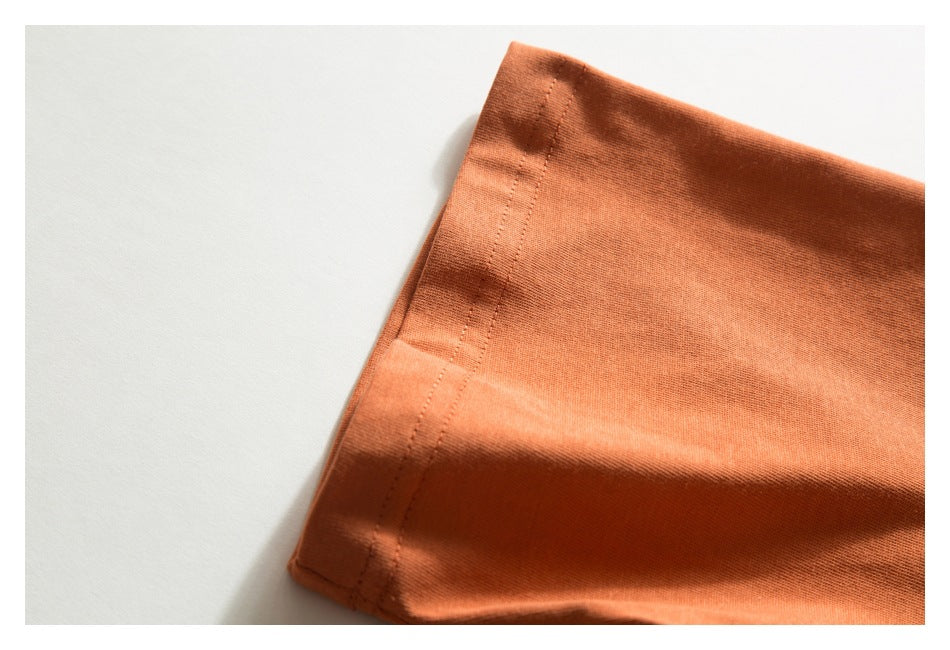 Close-up of a folded edge and double stitching on orange fabric.