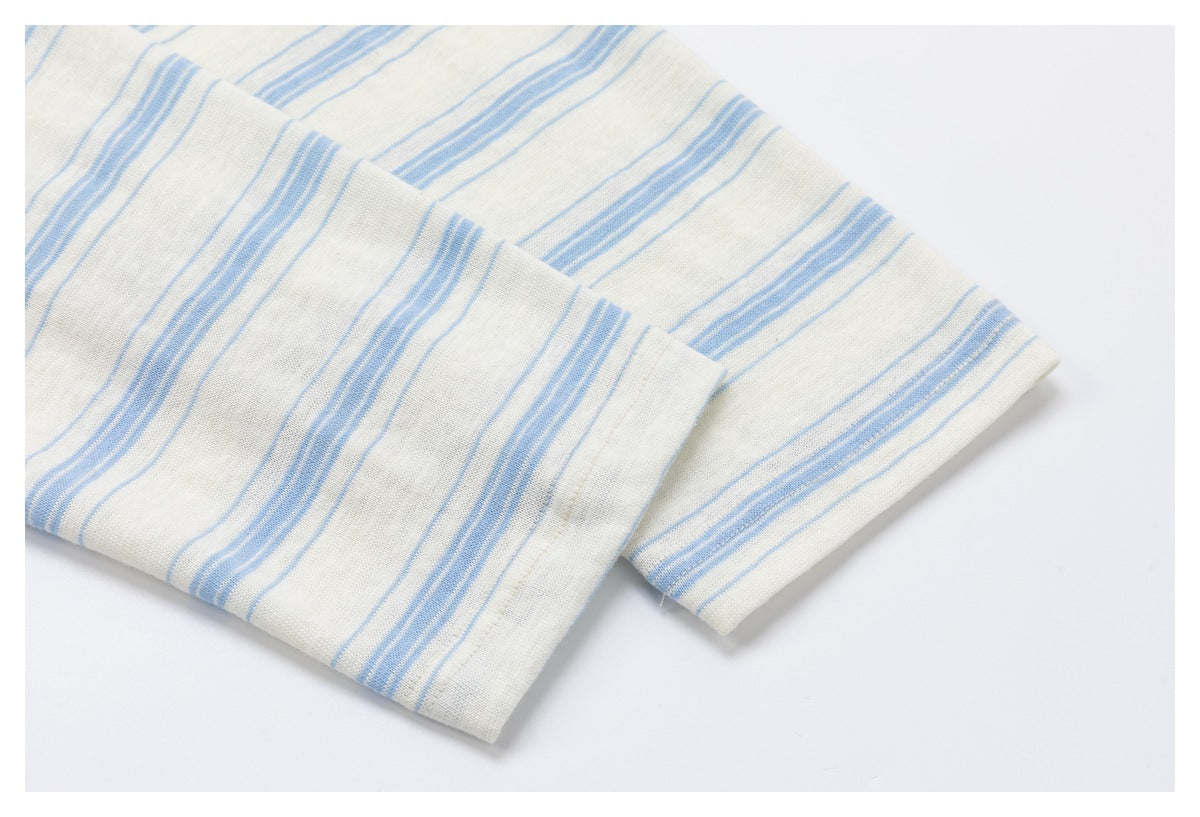 Close-up of folded off-white fabric with pale blue stripes and a stitched edge.