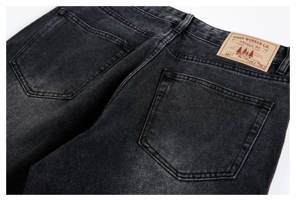 Close-up rear view of black jeans with two back pockets, belt loops, and a tan waistband patch.