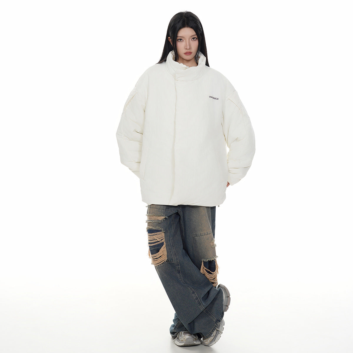Model wearing an oversized ivory padded jacket with a high collar and wide sleeves, paired with distressed dark jeans.