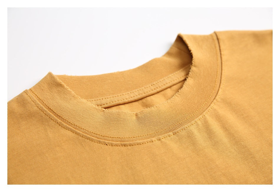 Close-up of the ochre T-shirt's ribbed crew neckline and collar stitching.