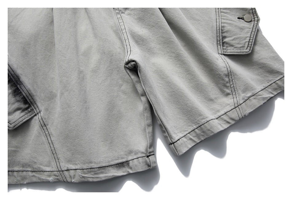 Close-up of light gray washed denim shorts showing the leg hems and cargo pocket flaps.