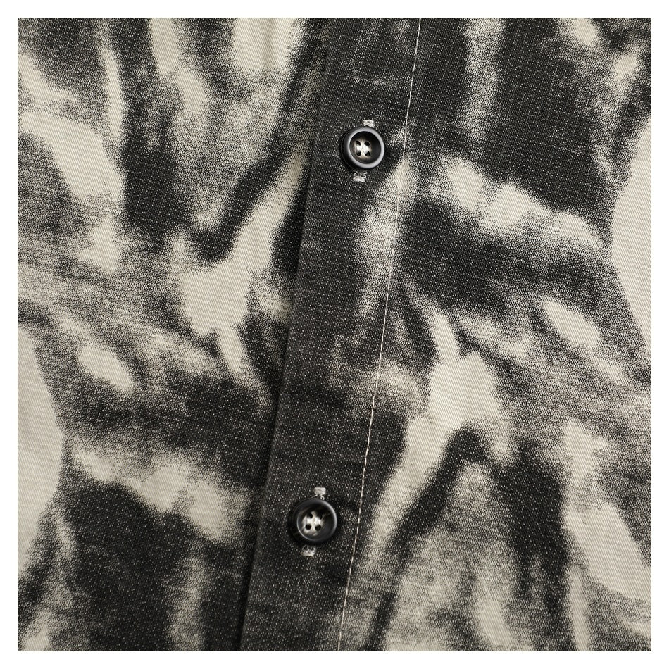 Close-up of a black and cream abstract-patterned garment with a button-front placket and dark buttons.