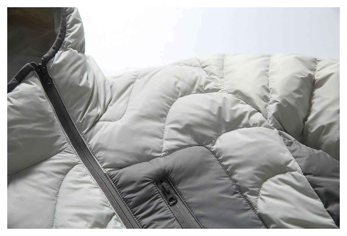 Close-up of a light gray quilted jacket front with dark gray panels and zippered pockets.