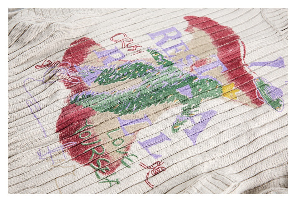 Close-up of a colorful red, green, and purple graphic across the ivory ribbed sweater's front.
