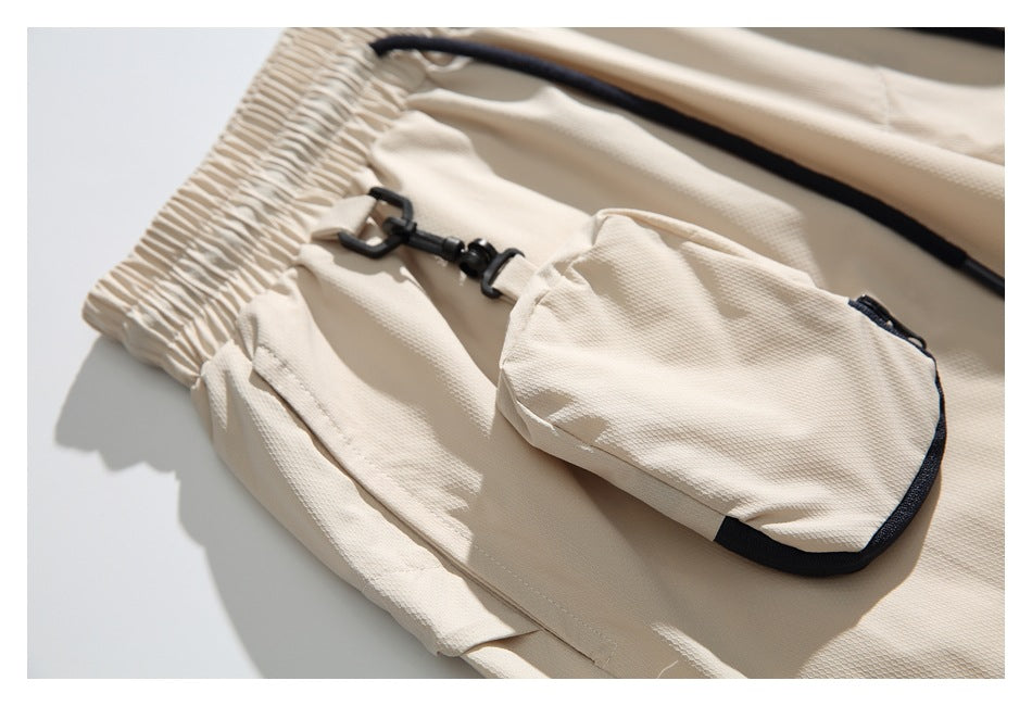 Close-up of cream pants showing the elastic waist, side pocket, and clipped-on pouch with dark trim.