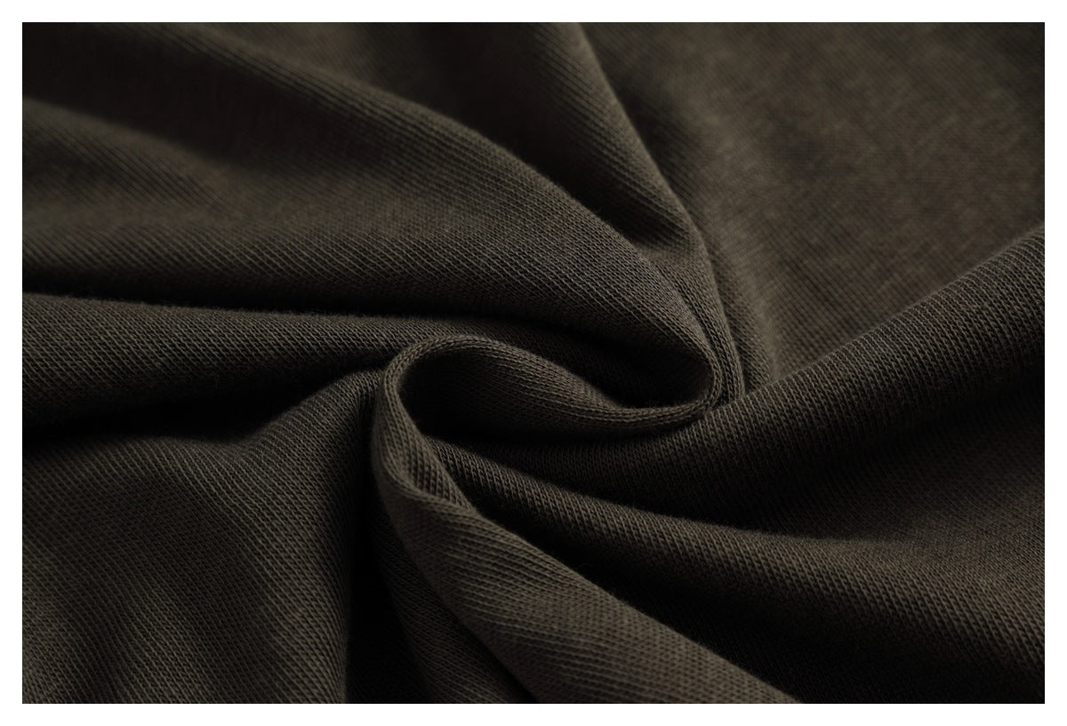 Close-up of dark charcoal-brown knit fabric gathered into folds, showing its surface texture.