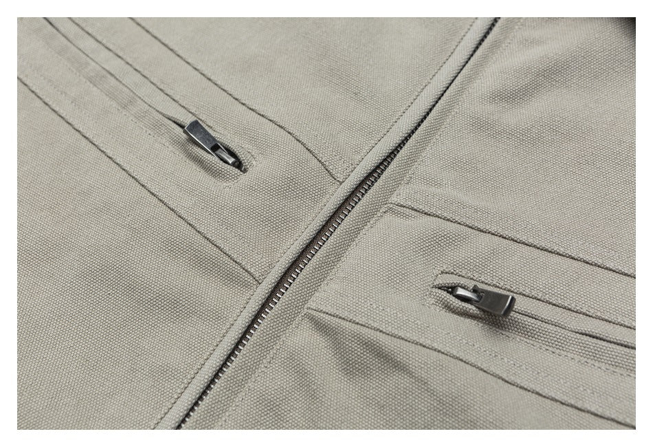 Close-up of a beige jacket's front zipper and two slim zippered pockets.